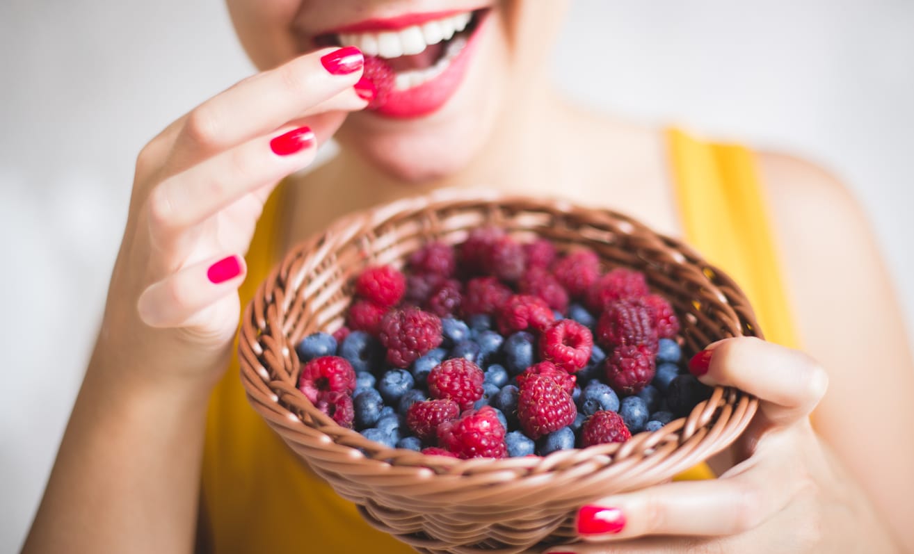 femme manger fruits frais rouges framboises myrtilles panier